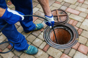 Sewer cleaning service worker clearing a clogged drain using hydro jetting